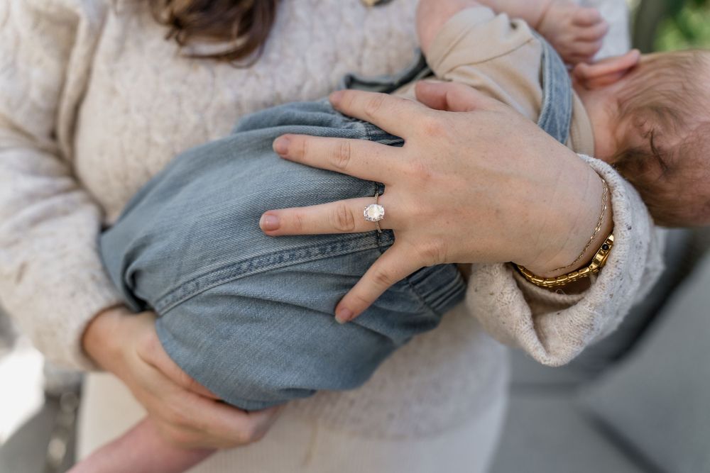 Sweet candid moment of parent snuggling with an infant wearing blue denim in Macedonia, Ohio in-home newborn photo session