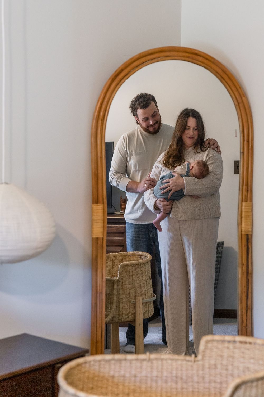 Family moment reflected in wooden-framed mirror showing parent holding baby in Macedonia, Ohio in-home newborn photo session