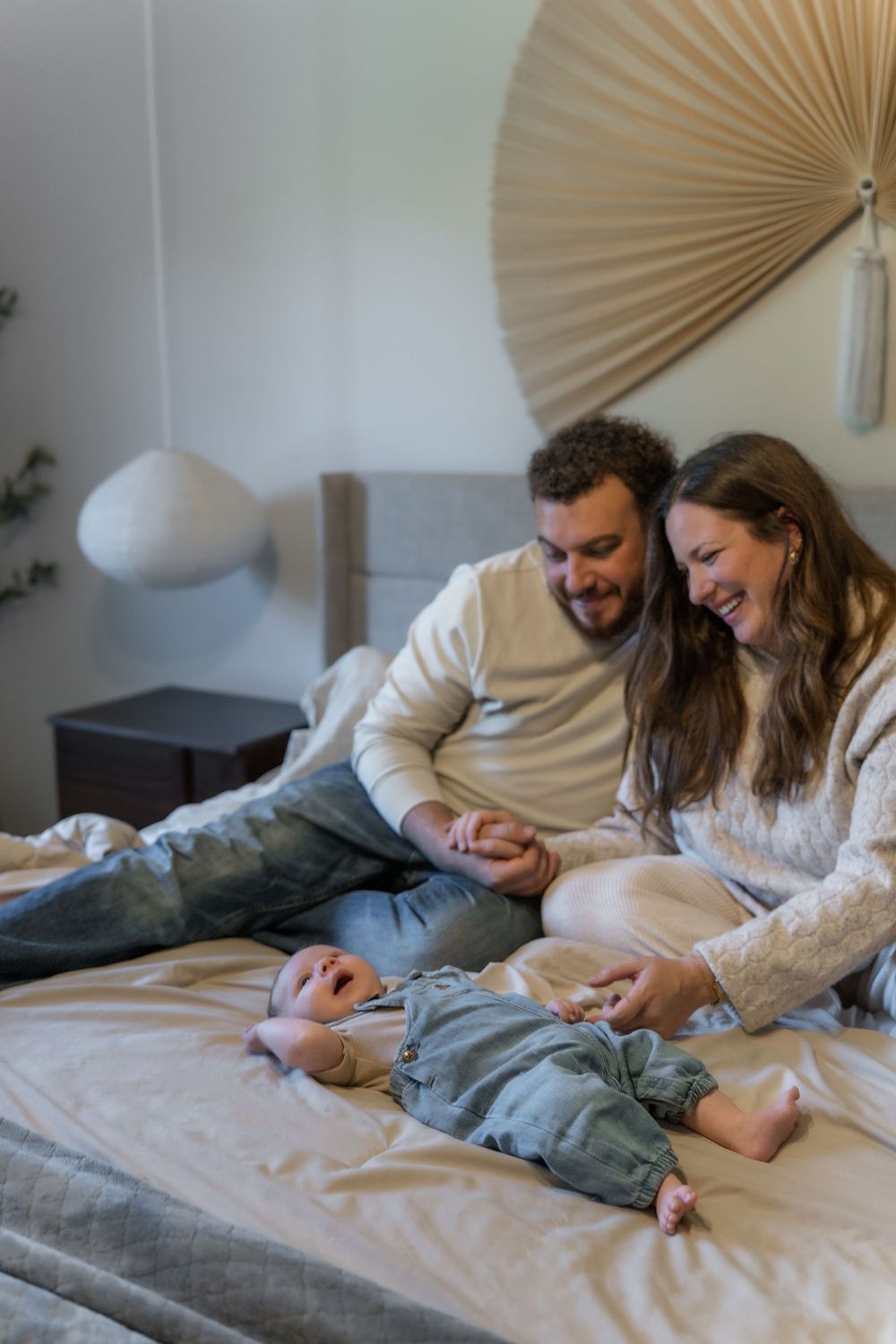 A happy family spending quality time together while relaxing on a white bed in Macedonia, Ohio in-home newborn photo session