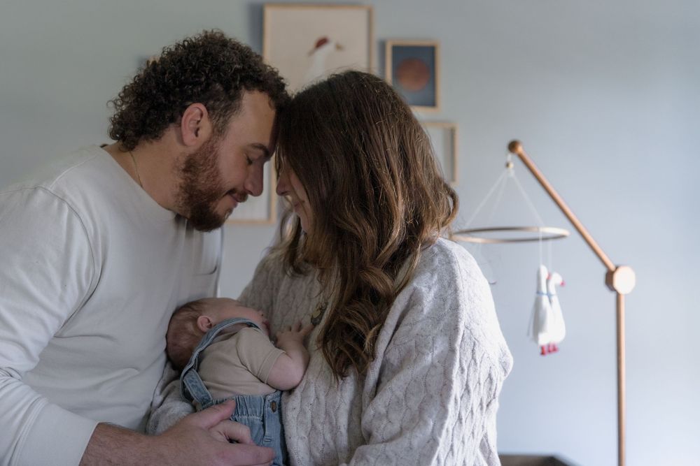 A family shares intimate moments together in a bright indoor setting with minimalist decor and warm lighting in Macedonia, Ohio in-home pic