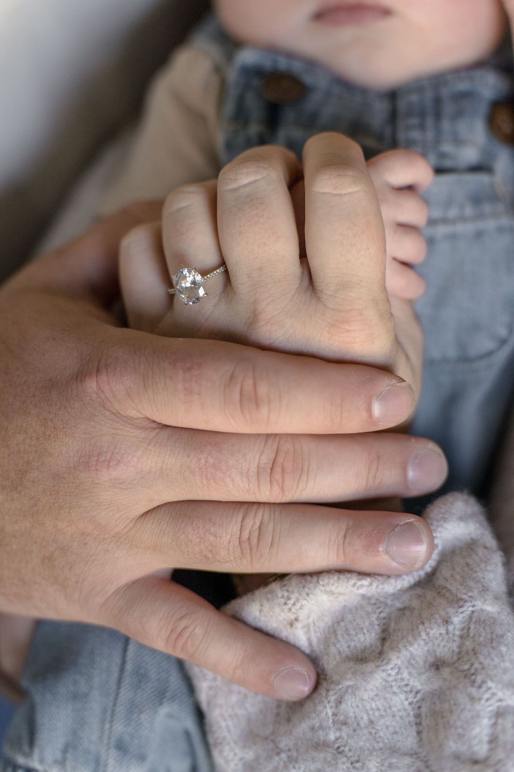 Close-up shots of hands wearing engagement ring while holding soft fabric in Macedonia, Ohio in-home newborn photo session