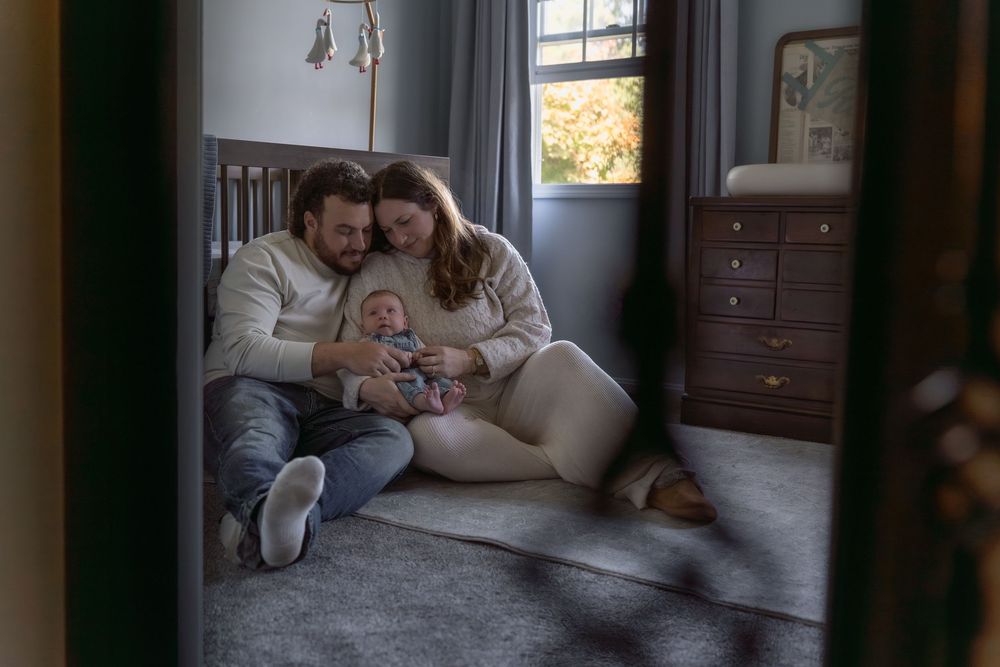 A cozy nursery corner with a dark wood dresser and changing pad next to a window in Macedonia, Ohio in-home newborn photo session