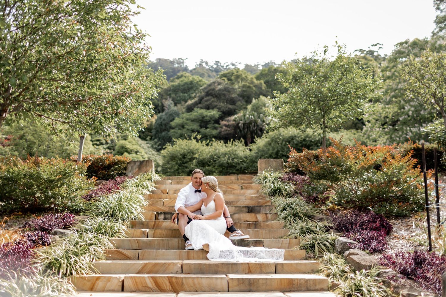 A terraced garden with stone steps features colorful flowering plants and natural landscaping in a hillside setting.