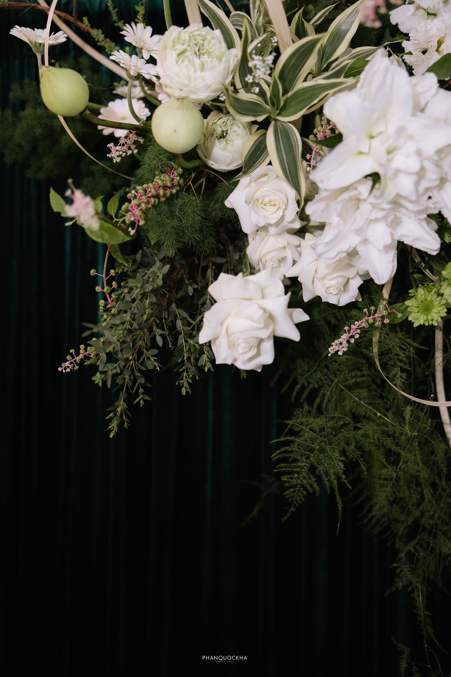Elegant floral arrangement featuring white roses, hydrangeas, and greenery against a dark velvet backdrop.