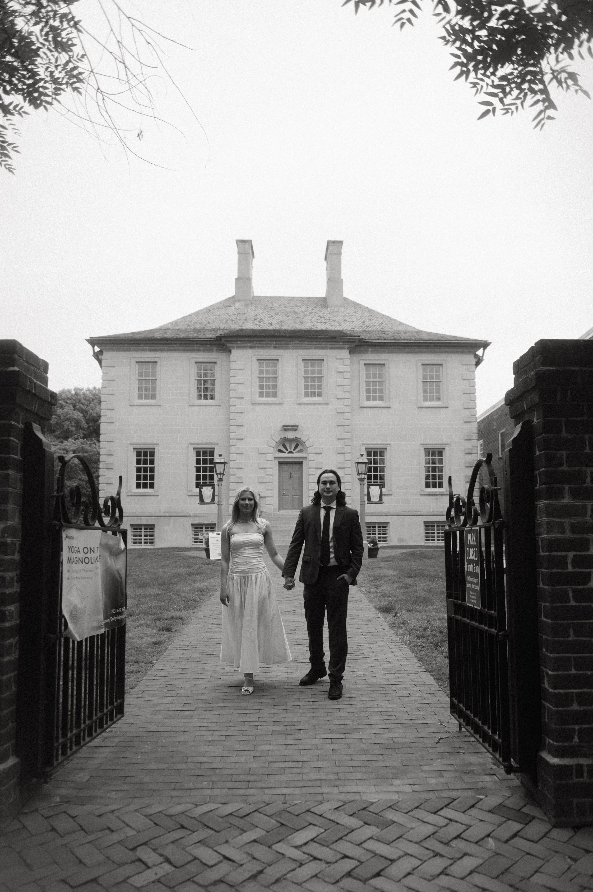 A wedding party walks along a path in front of a grand white Georgian manor house in a series of black and white photos.