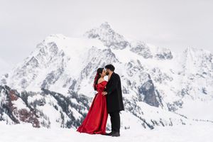Romantic couple standing together in winter attire against majestic snow-capped mountain peaks.