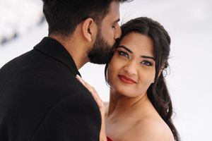 Two people share intimate moments of romance and affection in a light-filled professional photography setting.