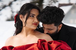 A romantic couple in formal attire embraces while dancing in winter against a snowy white backdrop.