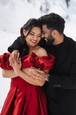 A couple in formal attire share an intimate dance moment, with the woman wearing a flowing red dress.