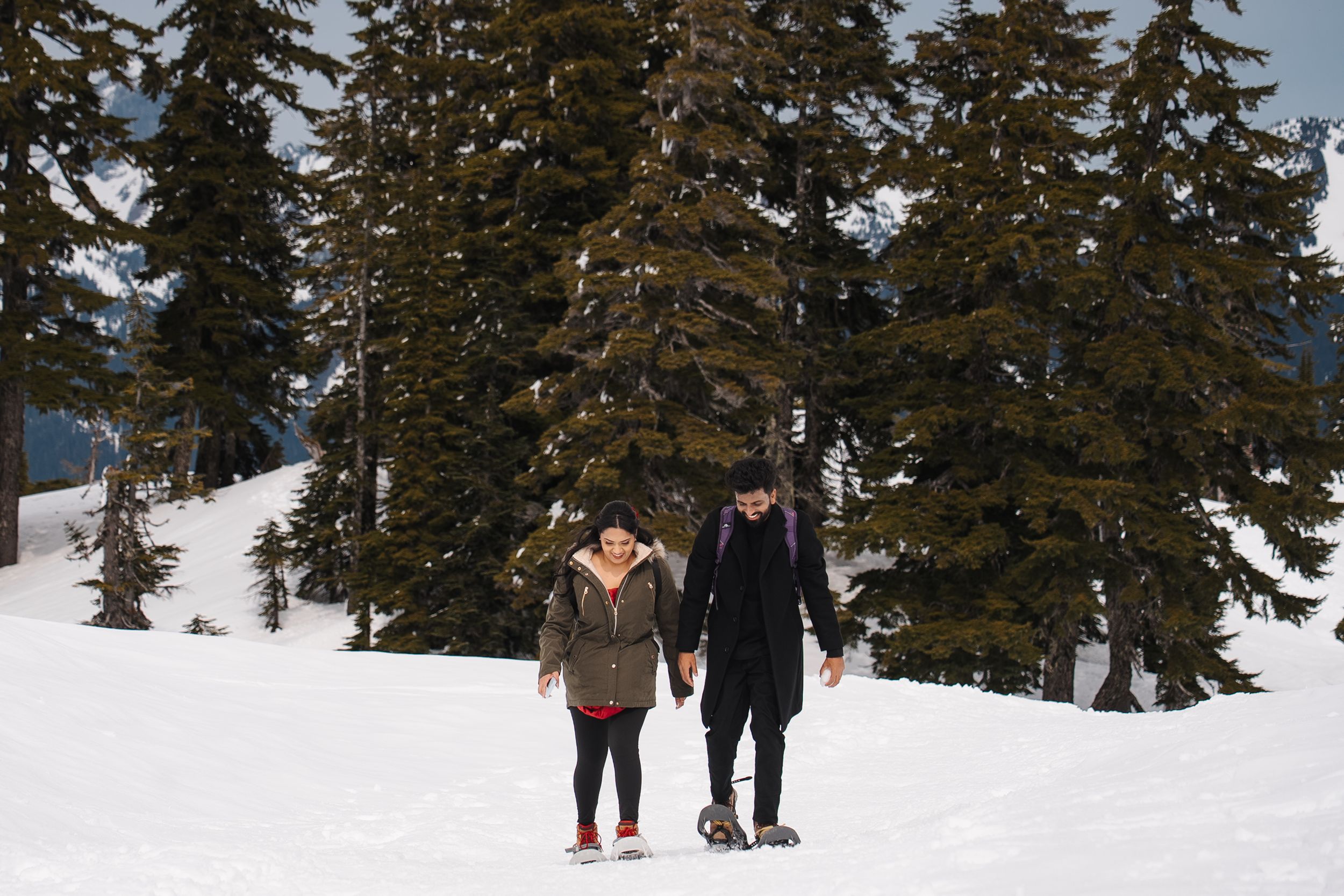 A group of skiers traverse through a snow-covered forest trail on a winter day as evergreen trees tower above them.