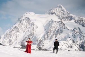 Skiers and snowboarders enjoying fresh powder on snowy mountain slopes beneath dramatic cloudy alpine peaks.