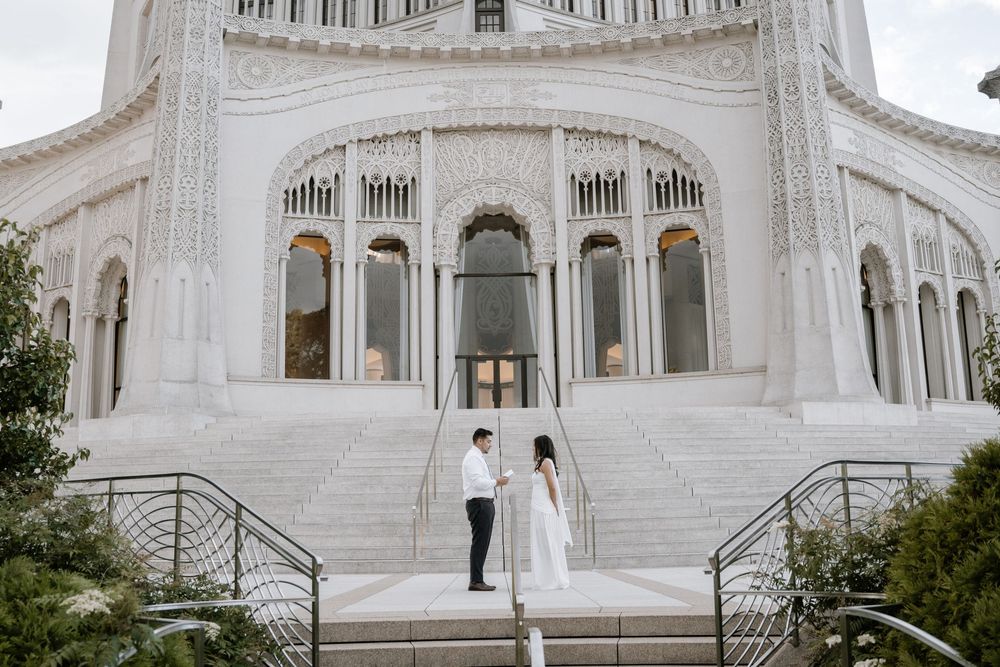 Romantic couple takes wedding photos in front of majestic white Baha'i Temple building in Wilmette, Illinois.