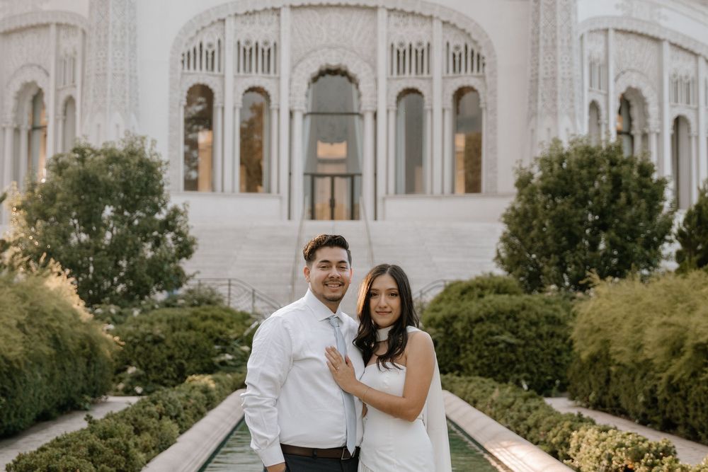 Wedding couple shares romantic moment in front of majestic Baha'i House of Worship with its ornate white domes.