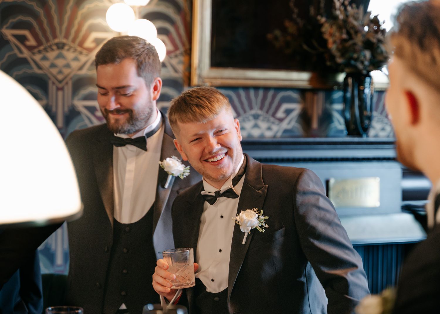 Well-dressed guests enjoying drinks and conversation at elegant evening reception.
