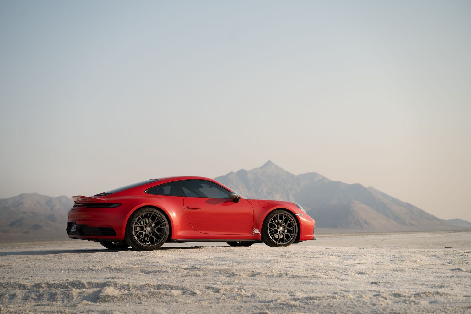 Red sports car photographed in a desert landscape with mountains in the background.