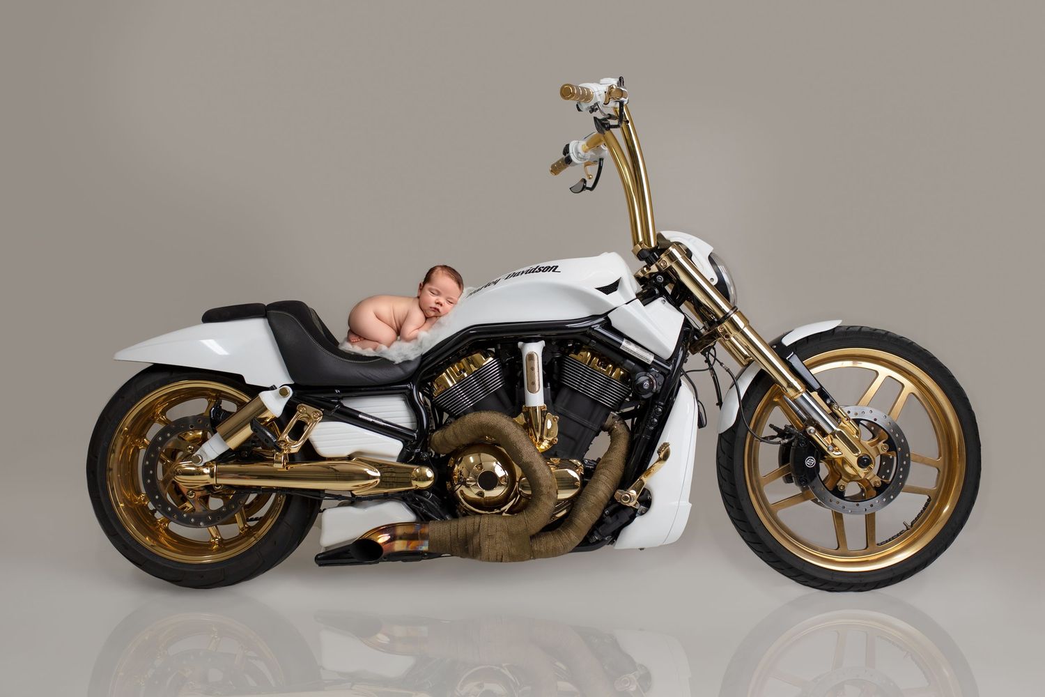 Creative newborn photography Springfield Lakes – baby safely composited onto white and gold motorcycle using Photoshop. Professional Ipswich