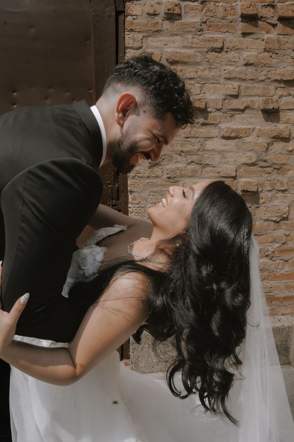 A romantic wedding kiss sequence showing four progressive moments against a rustic brick wall backdrop.