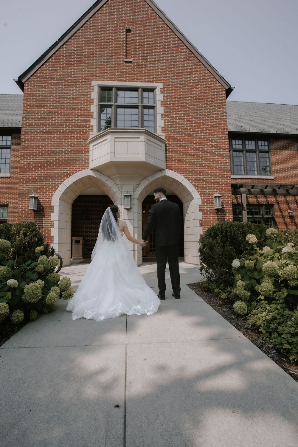 First look sequence showing couple meeting at brick church entrance with lush green bushes.