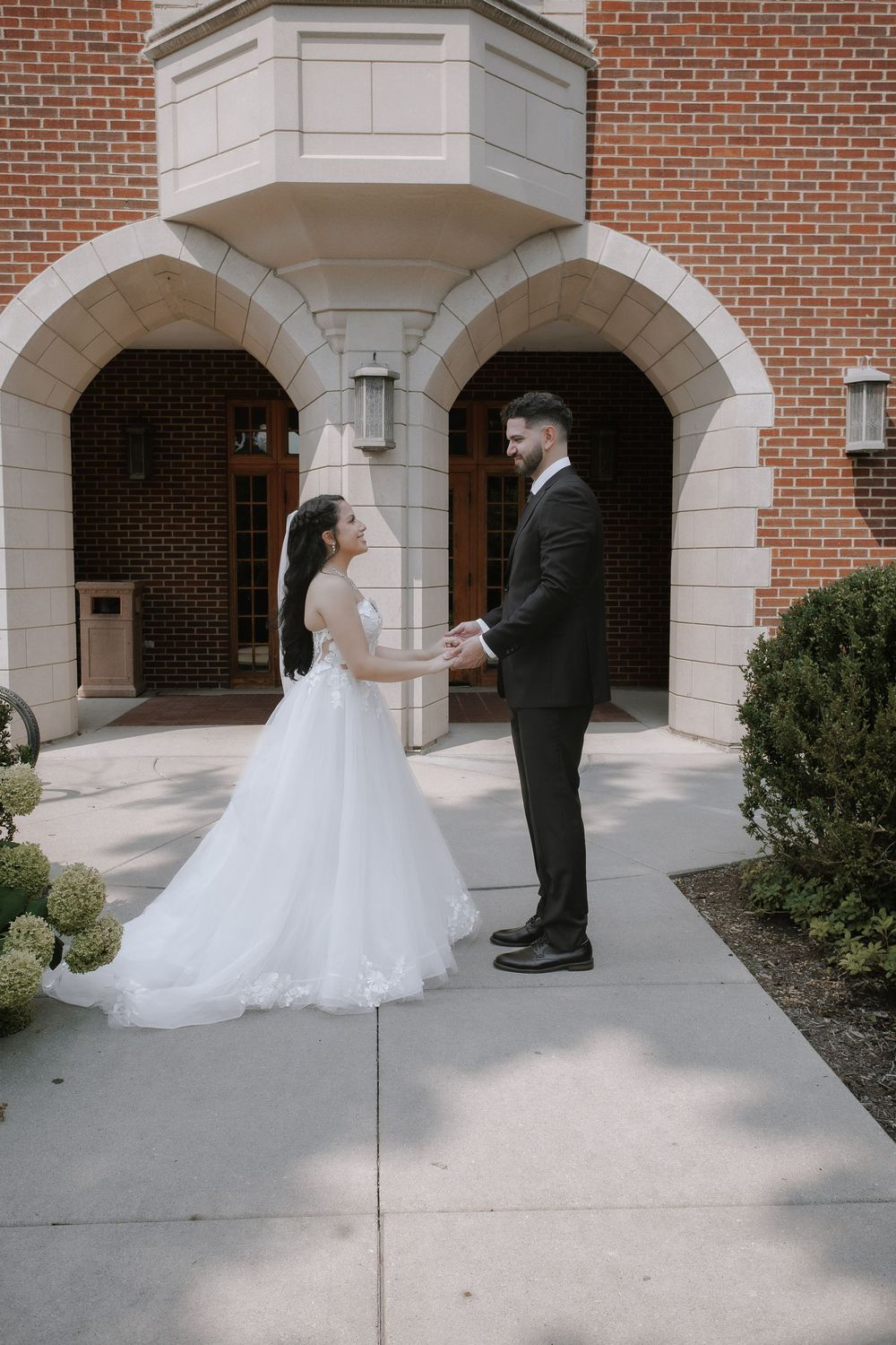A romantic wedding moment captured in a brick archway walkway at a traditional venue.