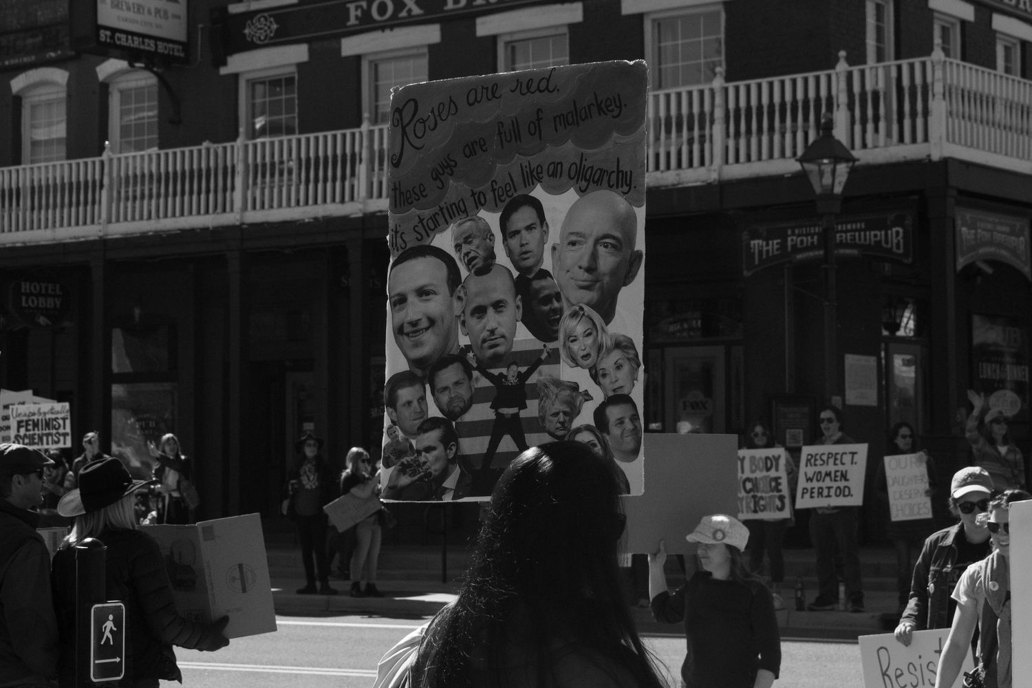 Protesters holding large illustrated sign at public demonstration in black and white photo.