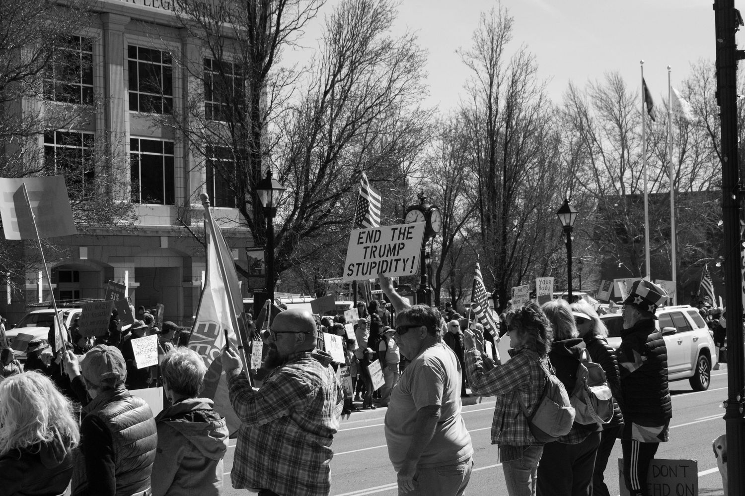 Black and white photo of street protesters carrying signs and flags in an urban area.