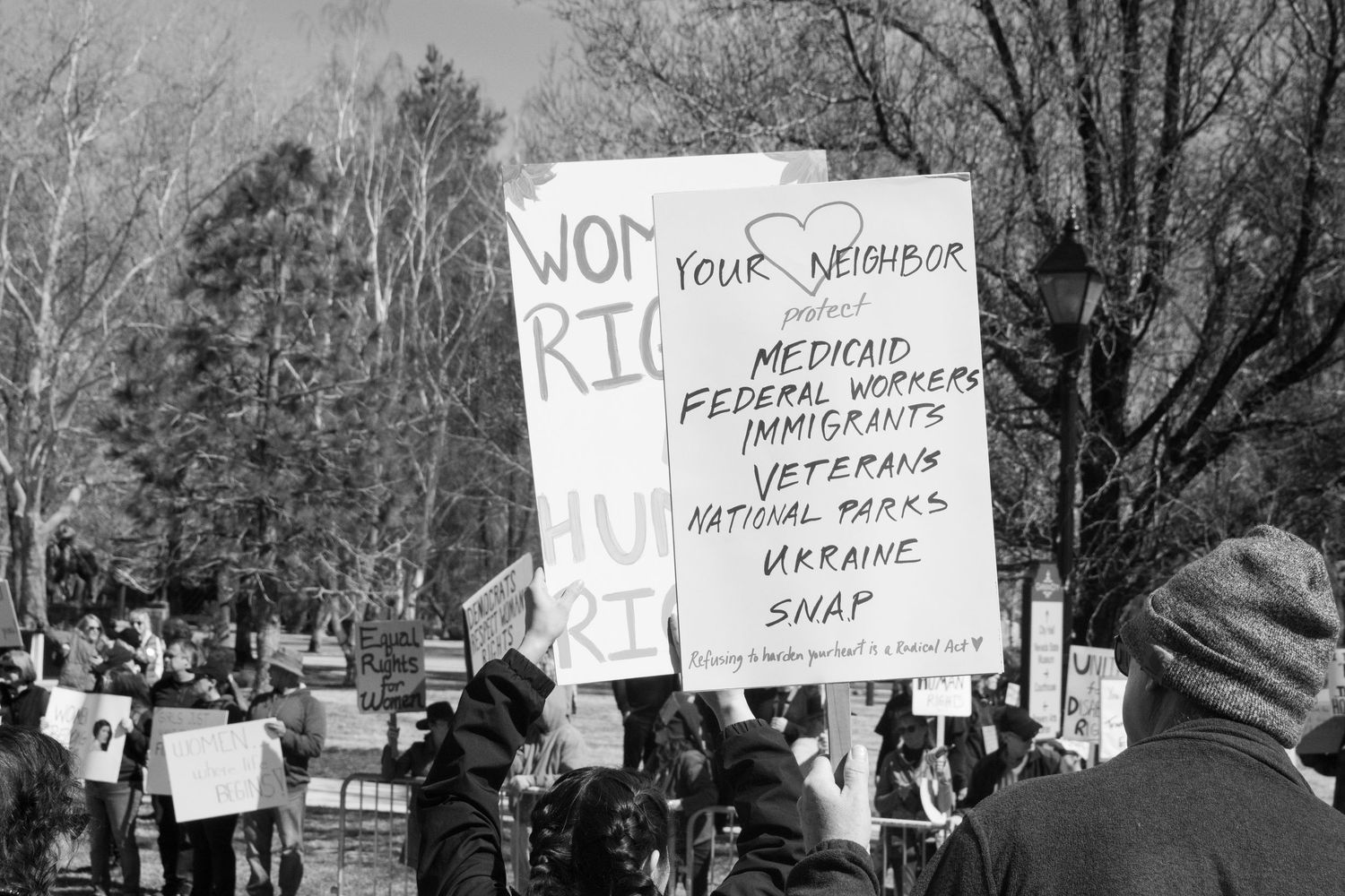 Protesters hold signs supporting Medicaid federal workers immigrants veterans national parks Ukraine SNAP.