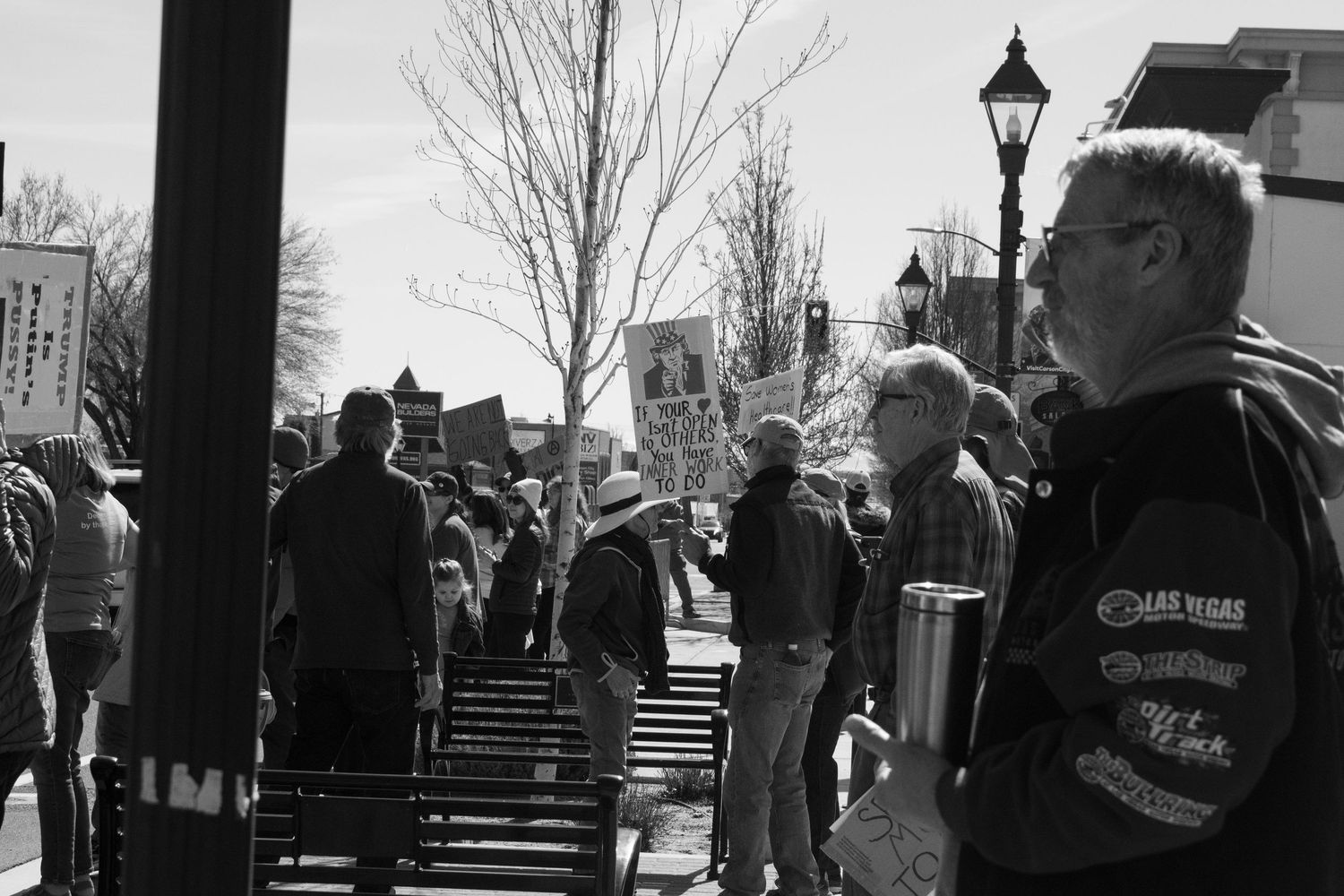 Crowd of protesters with signs gathered on a sidewalk during an outdoor political demonstration.