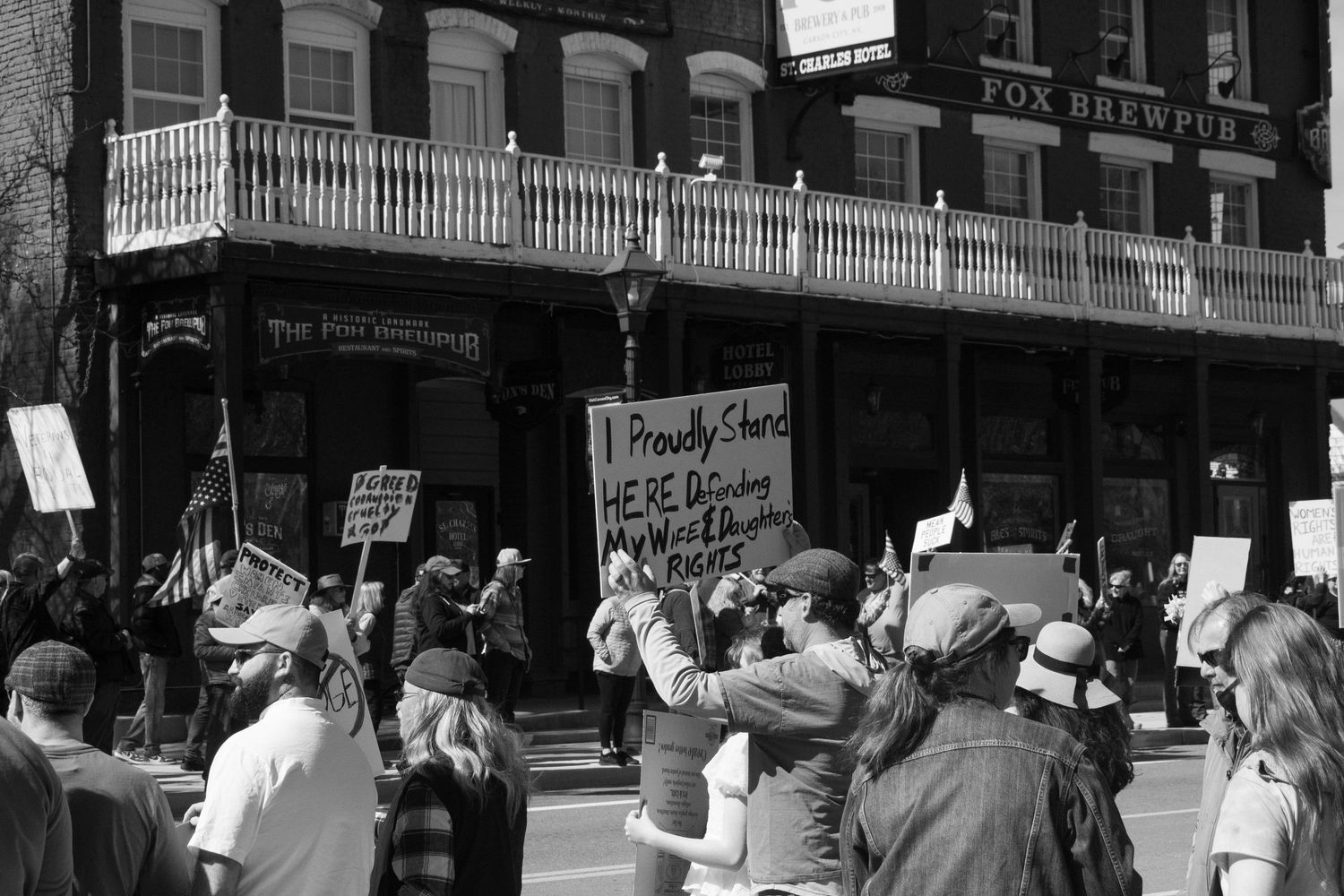 Black and white photo of protesters outside Fox Brewer building holding handmade signs at a rally.