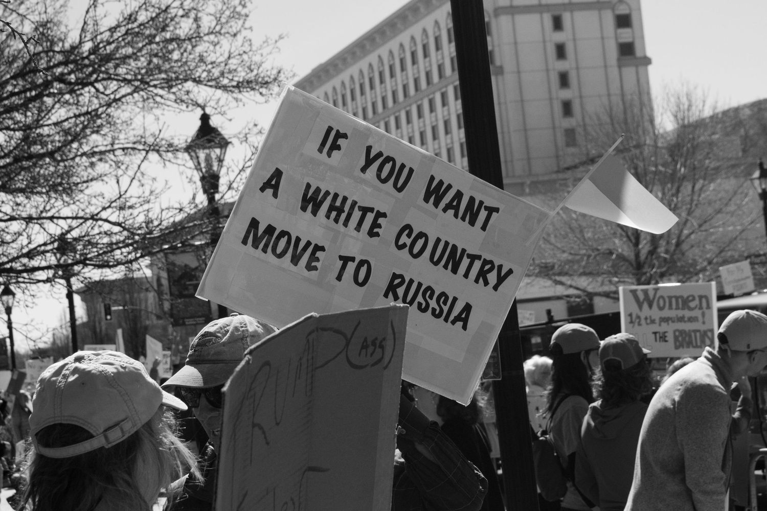 Protester holds sign reading If You Want a White Country Move to Russia at a public demonstration.