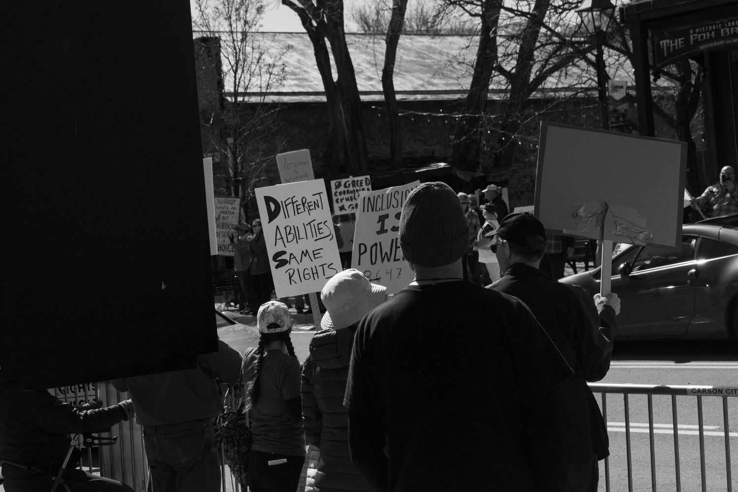 Black and white photo of protesters holding signs about rights and power at a street demonstration.