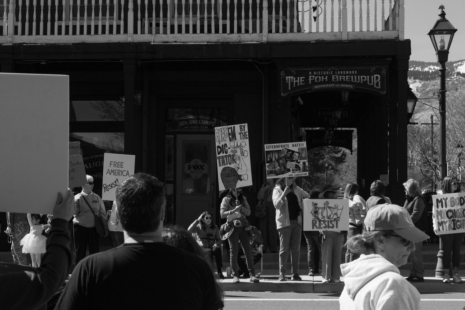 Black and white photo of protesters holding signs outside The Pen Omniplus building at street rally.