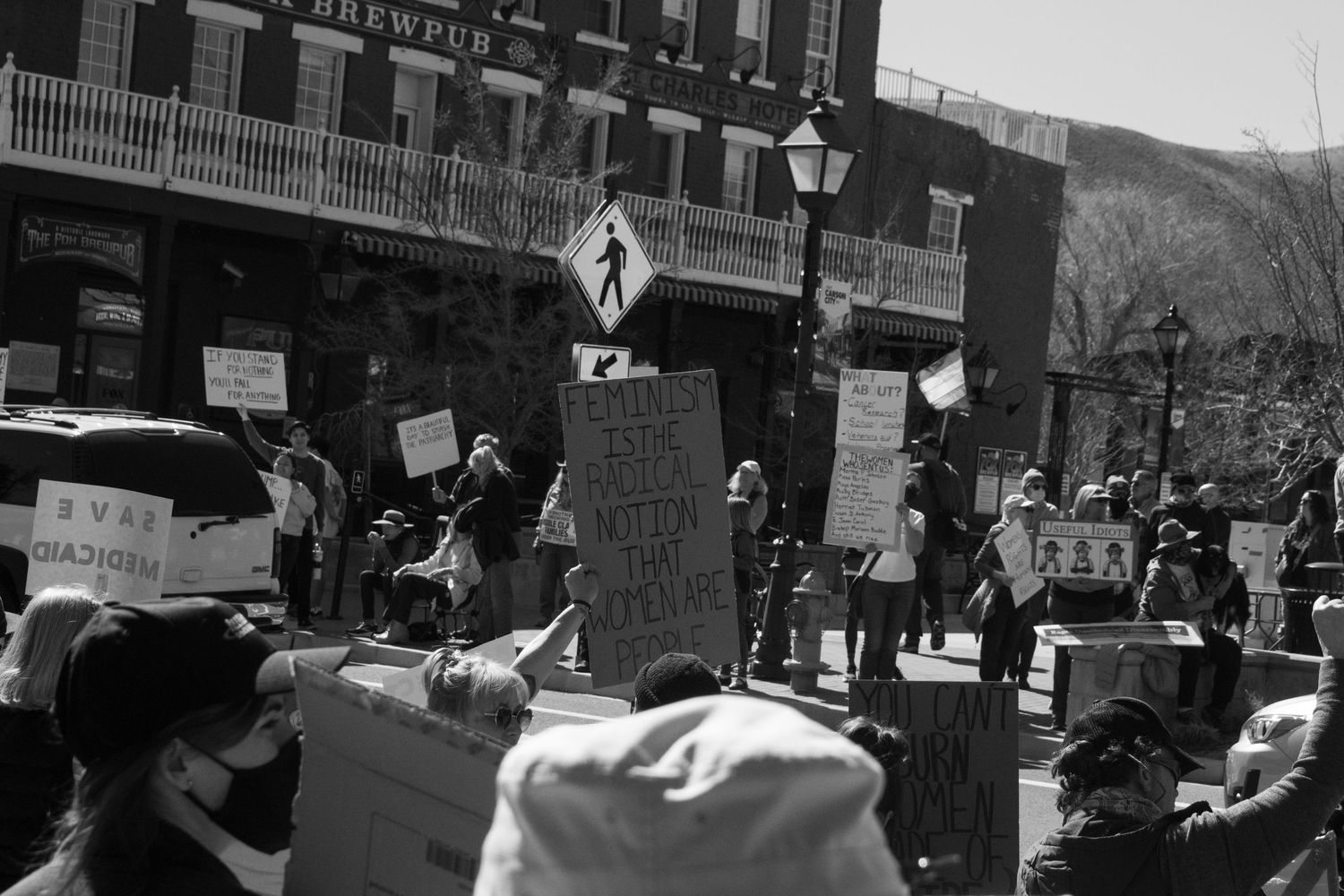 Black and white photo of a large crowd of protesters holding signs at an outdoor rally.