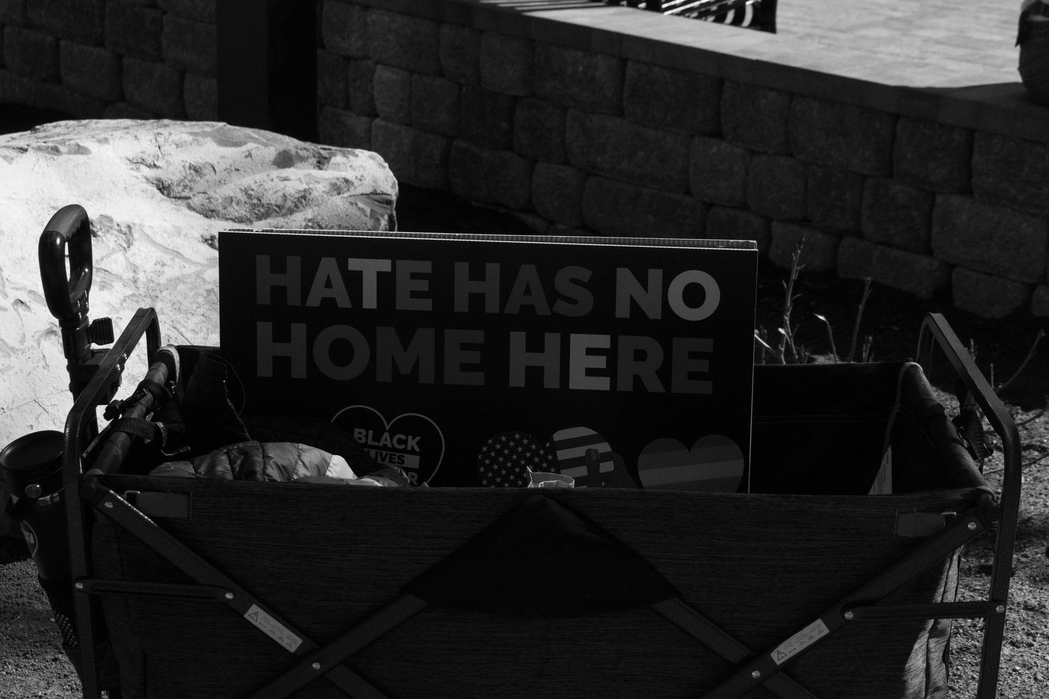 Black and white photo of a Hate Has No Home Here sign displayed in a wagon at a protest.