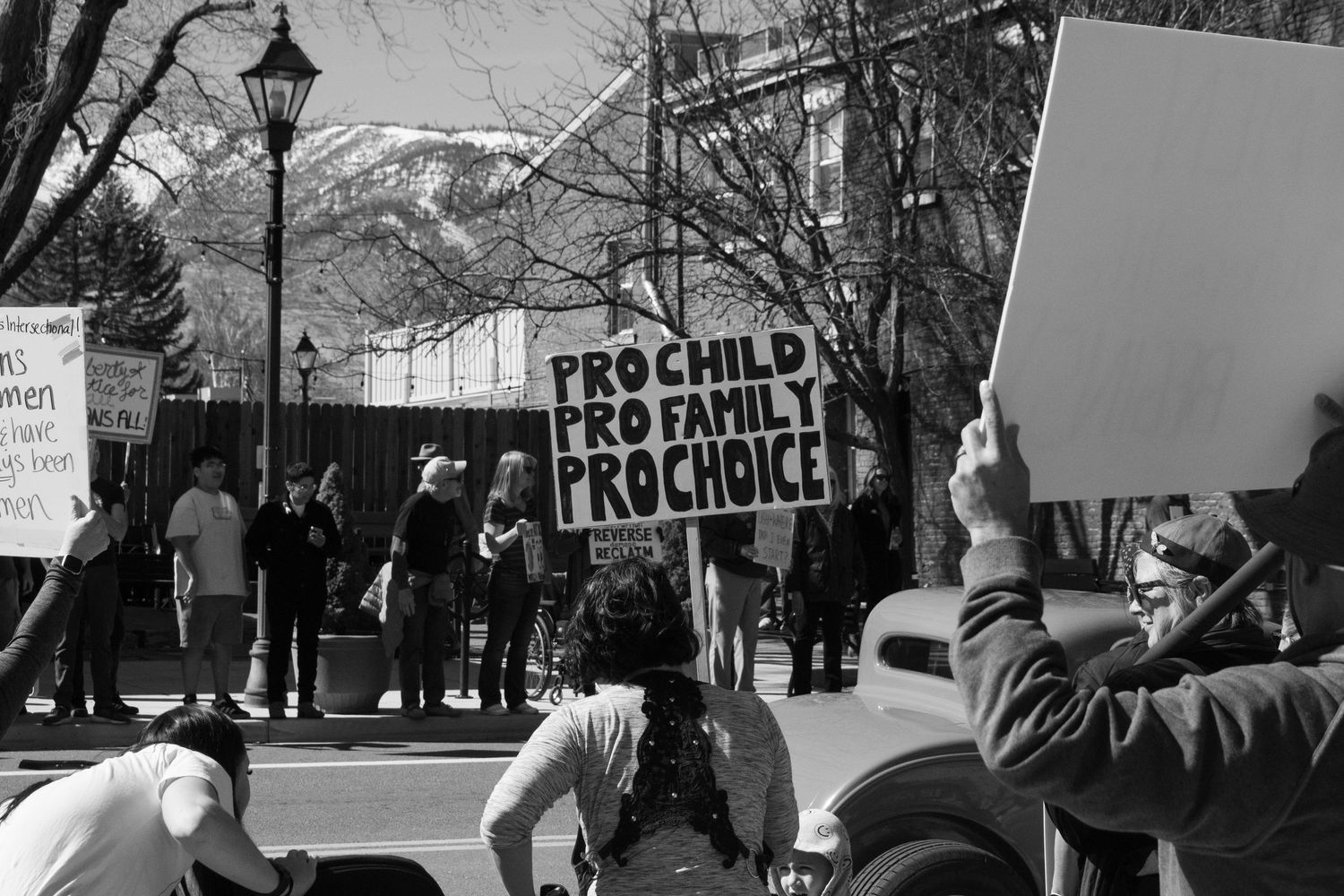 Black and white photo of protesters holding a Pro Child Pro Family Pro Choice sign at an outdoor demonstration.