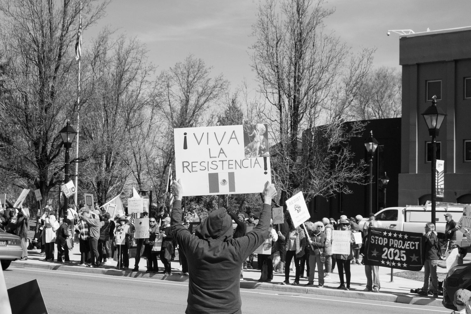 Demonstrator holds Viva La Resistencia sign amid large crowd of protesters lining a street.