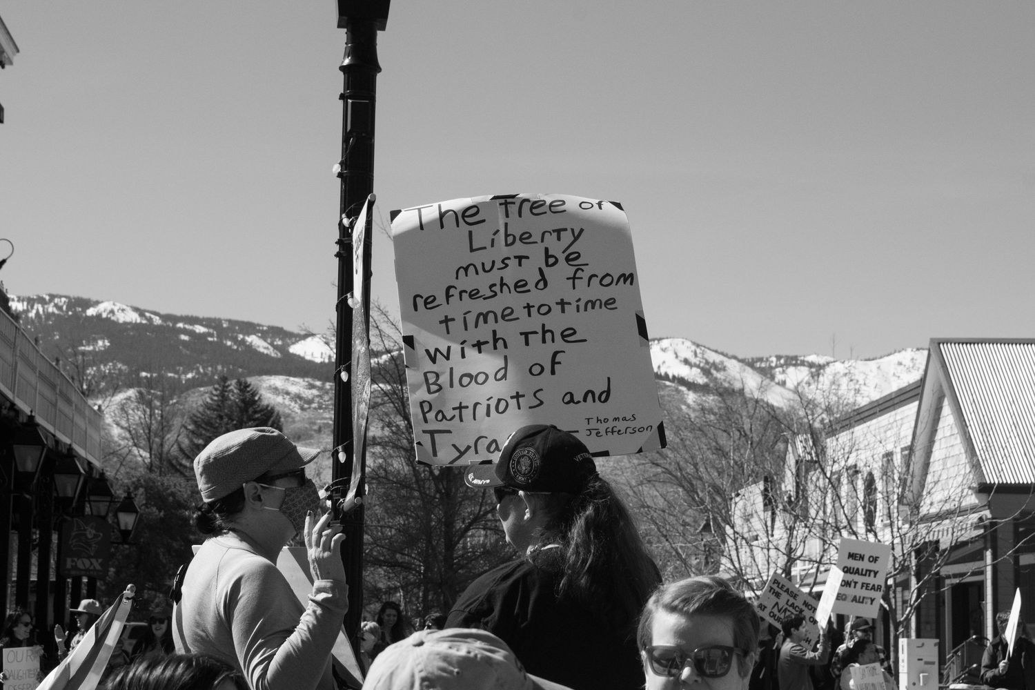 Black and white photo of a protester holding a sign quoting the Tree of Liberty must be refreshed speech.