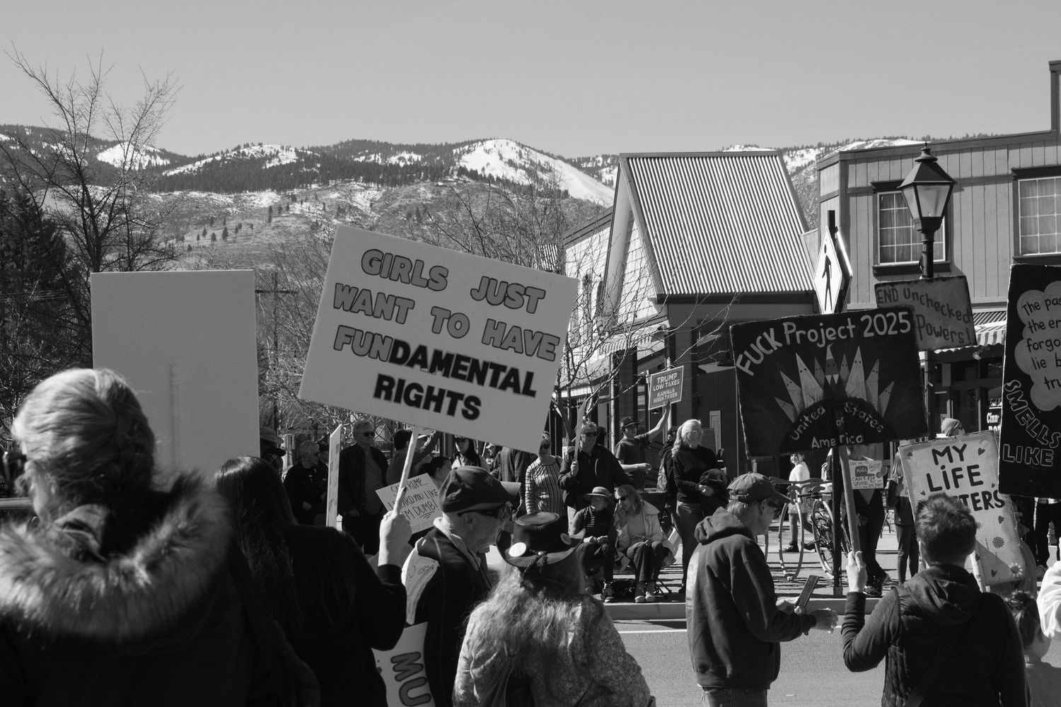 Black and white photo of protesters marching with a sign reading Girls Just Want to Have Fundamental Rights.