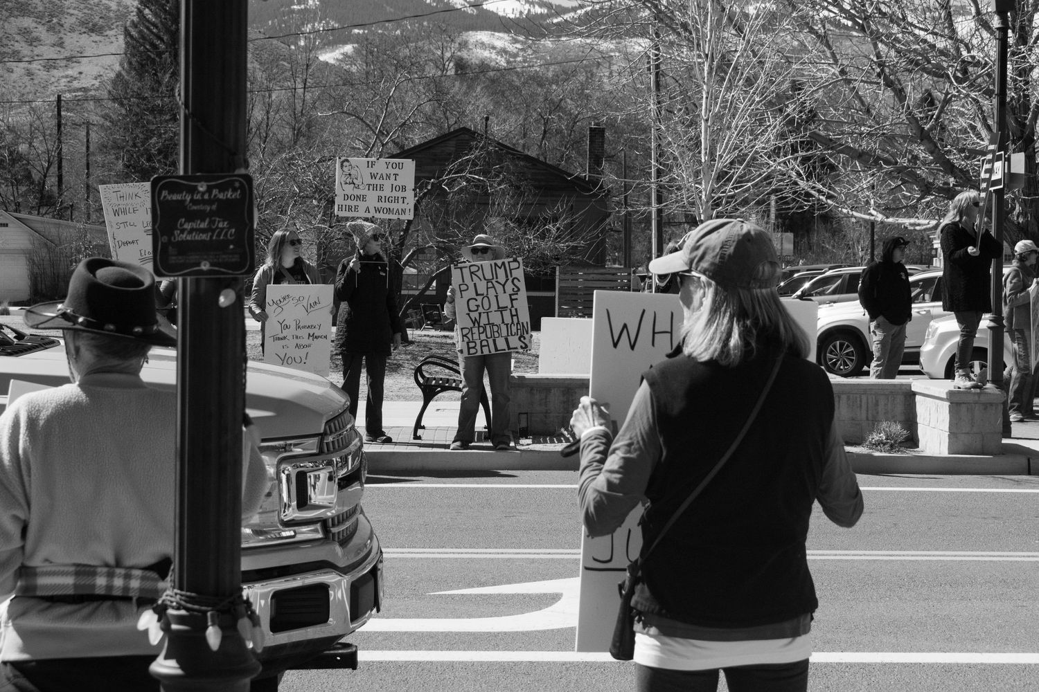 Black and white photo of protesters holding signs at a street corner demonstration.
