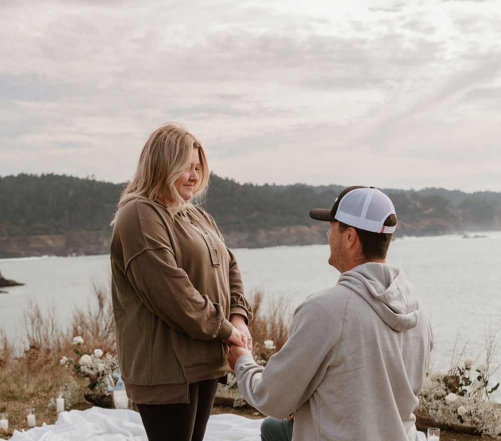 Two individuals share a special moment on a cliff edge with a beautiful ocean view.
