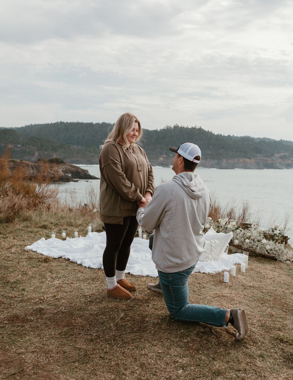A surprise proposal moment captured on a scenic cliff overlooking the water.