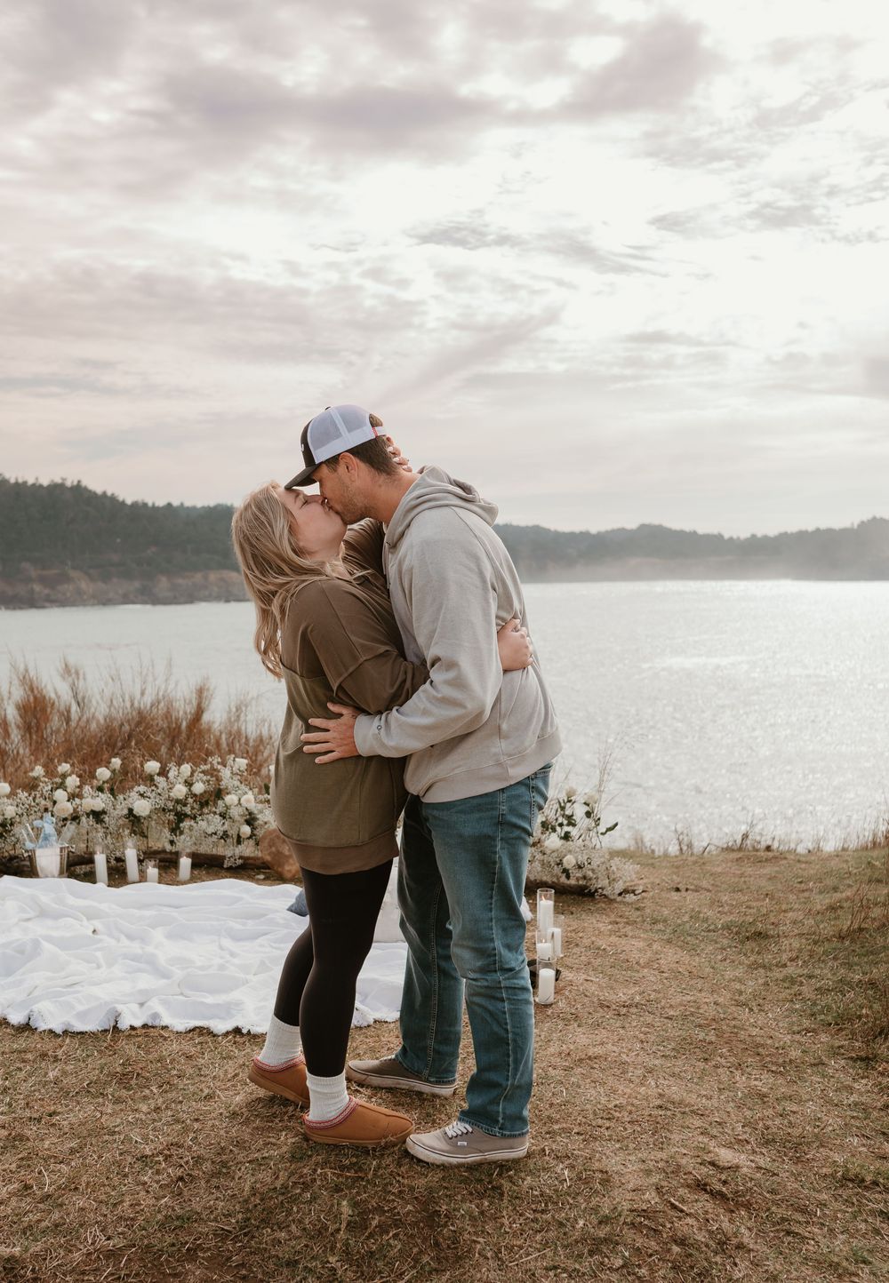 A couple embraces on a scenic cliff overlooking the bay after a romantic proposal.