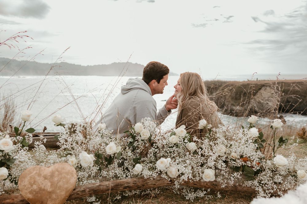 Dreamy landscape scene with floral arrangements and distant mountains.
