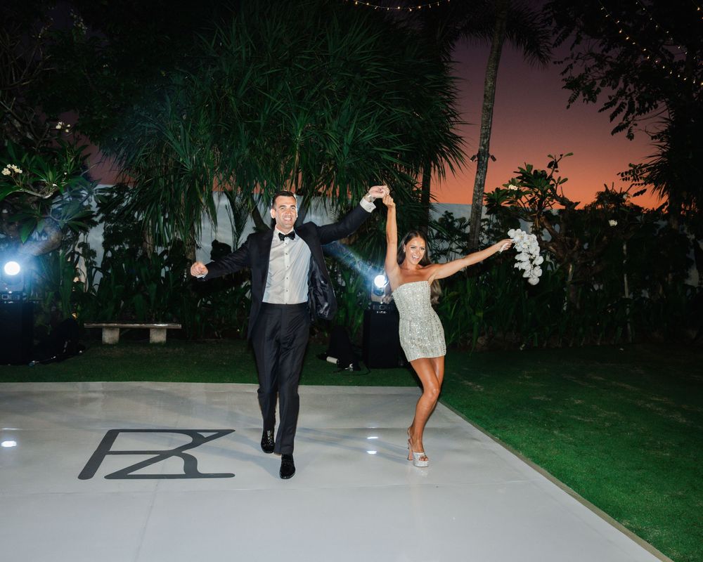 A couple dances together on a moonlit patio during an outdoor evening wedding celebration