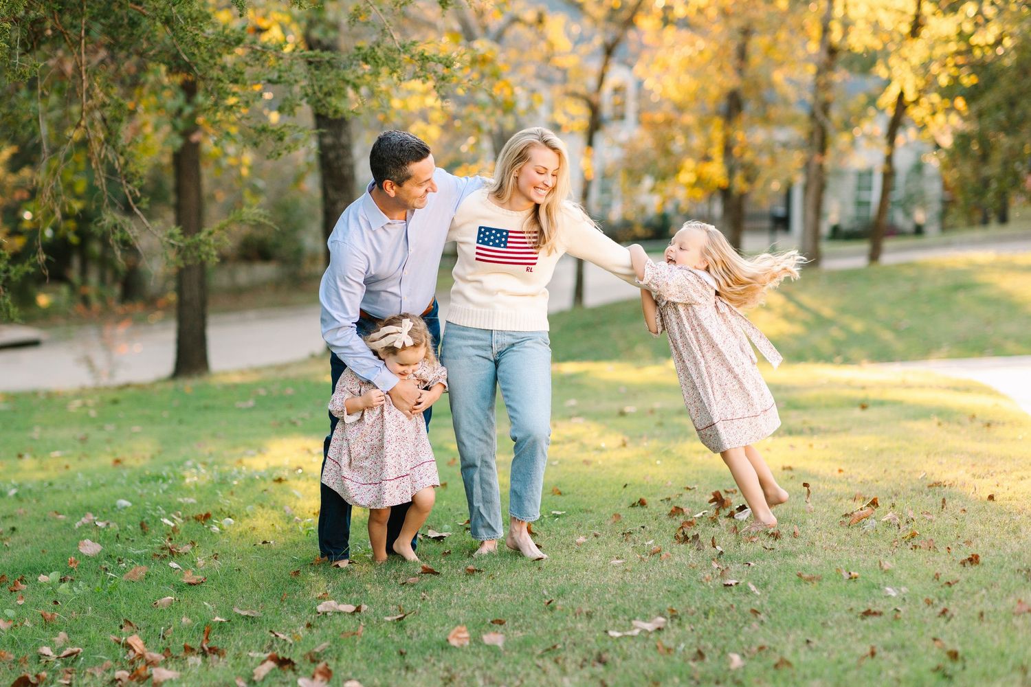 Family enjoying a playful autumn afternoon together in a sunlit park with golden fall foliage.