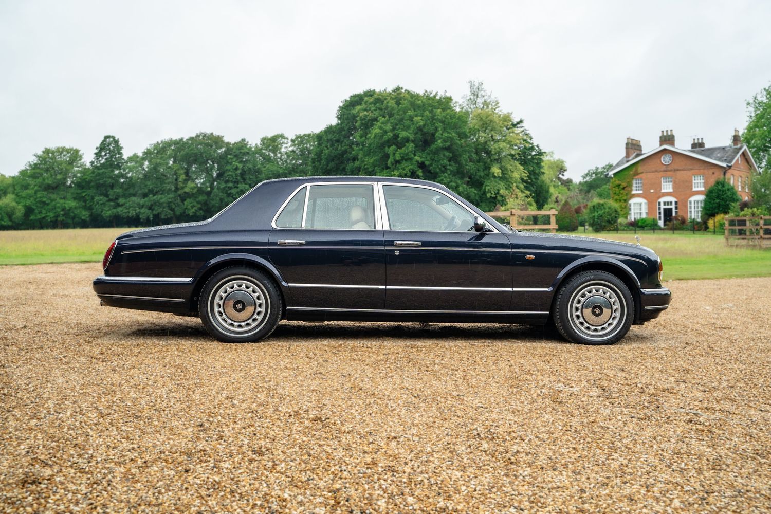 Wide angle shot of a stately black luxury car displayed in front of a brick building.
