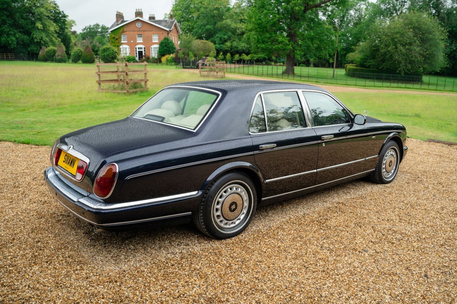 Elegant vintage luxury sedan photographed against rural barn and countryside setting.
