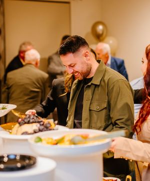 People gather around tables in a casual dining setting with white plates and casual attire.