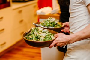 Chef plates fresh ingredients on stone dishes in a bustling restaurant kitchen.