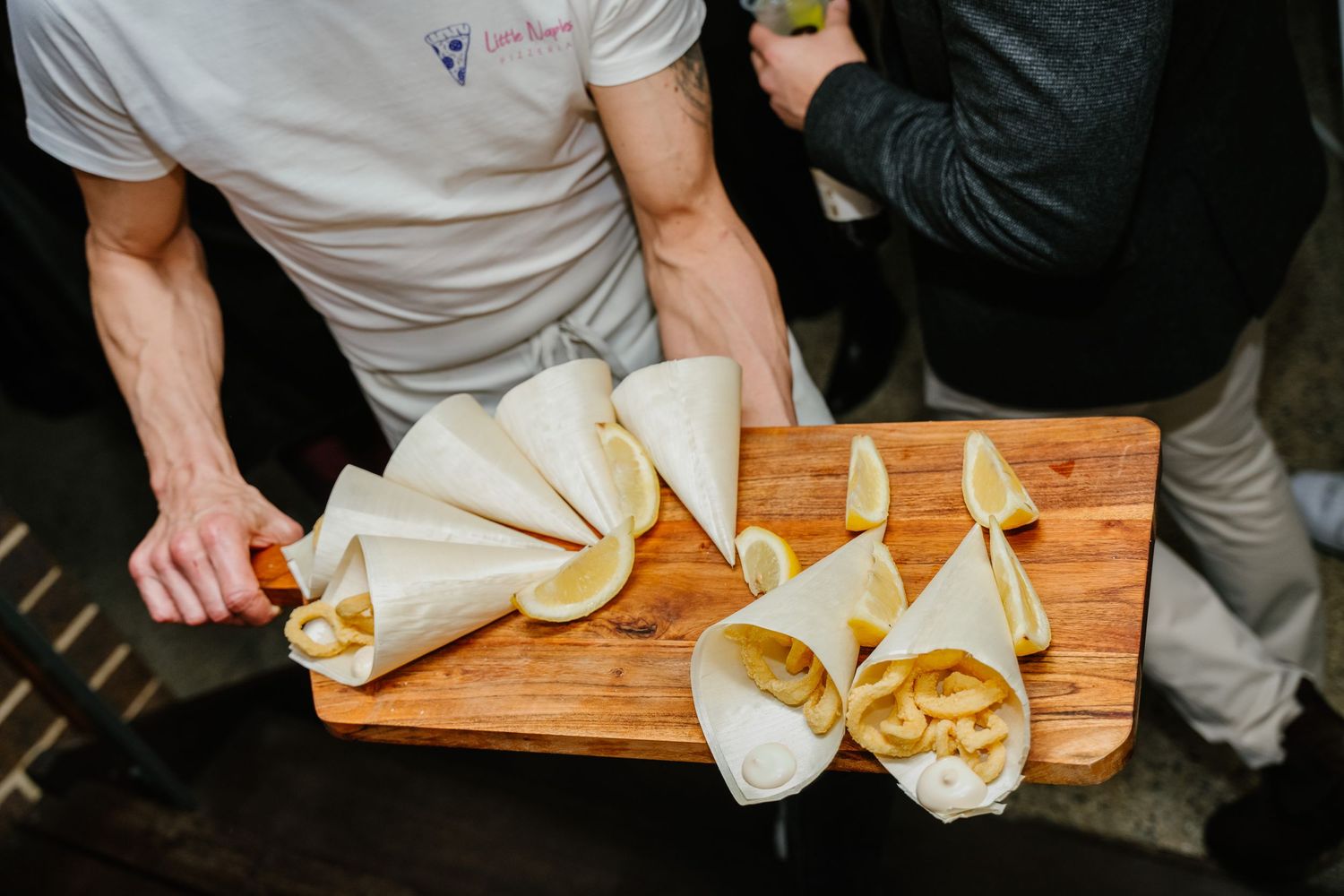 Person wrapping soft dough or pastry in a wooden board surface in a professional kitchen setting.