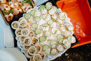 Elegantly arranged sliced cucumbers and sushi rolls on white platters in a restaurant setting.